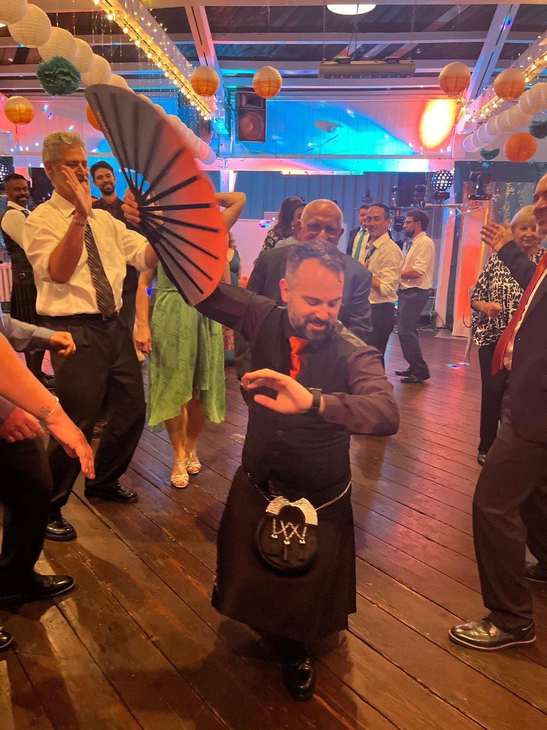 A wedding guest dancing at the reception with a big ombre Daftboy clack fan