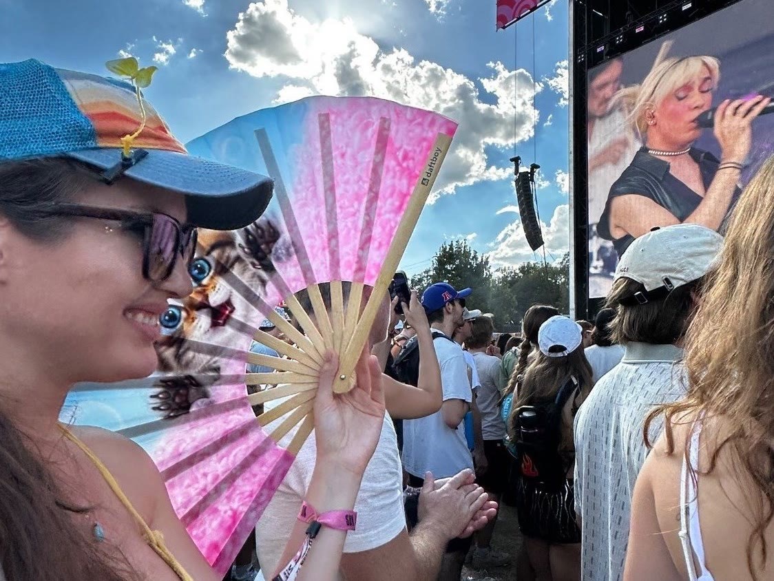 A festival fan holding a custom Daftboy double-sided kitten fan